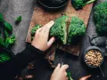 Manos cortando brócoli, un alimento rico en silicio, junto a guisantes y cacahuetes.