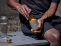 Hombre abre frasco de creatina. ¿La creatina te pone nervioso? Prepárate para tu ritual diario.