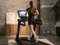Mujer pelirroja corre en cinta, entrenando en casa con estilo.