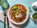 Bowl con arroz, frijoles, guacamole, pico de gallo y trozos de boniato y tofu, un festín de comidas vegetarianas ricas en proteínas.