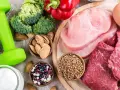 Alimentos para una dieta para ganar masa muscular y definir: pesas, brócoli, pimientos, carnes, huevos, yogur, almendras y legumbres.