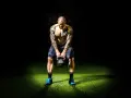 Hombre tatuado realiza press militar con kettlebell, enfocado en su entrenamiento.