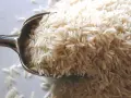Cuchara llena de arroz basmati. Aunque la crema de arroz engorda, este grano es un carbohidrato básico.