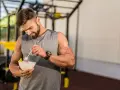 Hombre con barba en gimnasio, comiendo ensalada. Demuestra que se puede ganar músculo en déficit calórico con la dieta adecuada.
