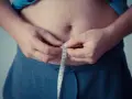 Man measuring waist with tape. A step towards understanding como activar la autofagia for better health.
