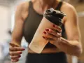 Mujer con uñas rojas sostiene un batido. ¿Los BCAA engordan? La respuesta depende de tu dieta.