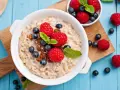 Un tazón de avena con frambuesas, arándanos y pasas. ¡Cuidado! La avena engorda si no se consume con moderación.