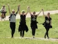 Cuatro mujeres celebran tomadas de la mano, con los brazos en alto, mientras caminan por un sendero. Su **velocidad media andando** parece alegre y enérgica.