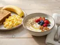 Desayuno con tostadas, huevos revueltos, plátano, yogur con frutos rojos, avena y nueces.