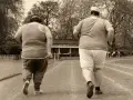 Dos personas con sobrepeso corren en una pista de atletismo. El andar adelgaza, y ellos lo saben.