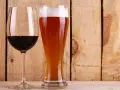 Copa de vino tinto y vaso de cerveza dorada con espuma. ¿Qué engorda más la cerveza o el vino? La respuesta está en las calorías.
