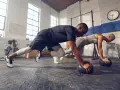 Pareja haciendo cardio en casa, en posición de plancha con balones medicinales.