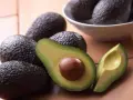 Aguacates frescos, uno cortado por la mitad mostrando su semilla, perfectos para comer aguacate todos los días y disfrutar de su cremosidad.