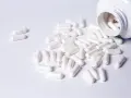 Cápsulas blancas derramadas de un frasco. Descubre para qué sirven los BCAA en mujeres y cómo pueden apoyar tu bienestar.