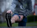 Hombre estirando la pierna antes de correr con agujetas.