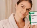 Mujer sonriente con bata, sosteniendo una caja de Magnesio Citrato Puro. Una dosis de magnesio para evitar calambres y mejorar la energía.