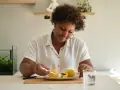 Mujer sonriente disfruta de croquetas de patata, un carbohidrato delicioso, con un vaso de agua.