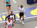 Corredores cruzan la meta en la media maratón de Europa. Una mujer saluda, celebrando su logro.