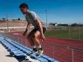 Corredor realiza ejercicios pliométricos subiendo escaleras en un estadio.