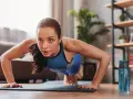 Mujer concentrada haciendo flexiones, parte de sus ejercicios de fuerza en casa.