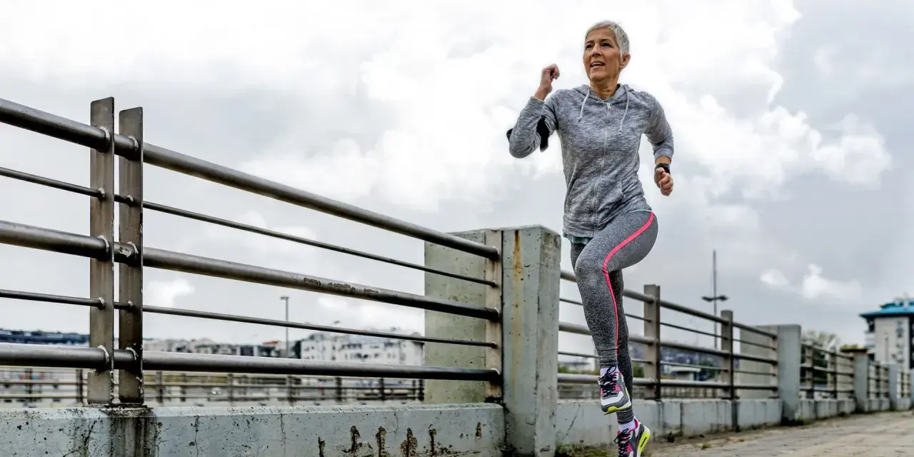 Mujer mayor corre por un paseo marítimo. ¡Una guía sobre cómo empezar a correr para principiantes!
