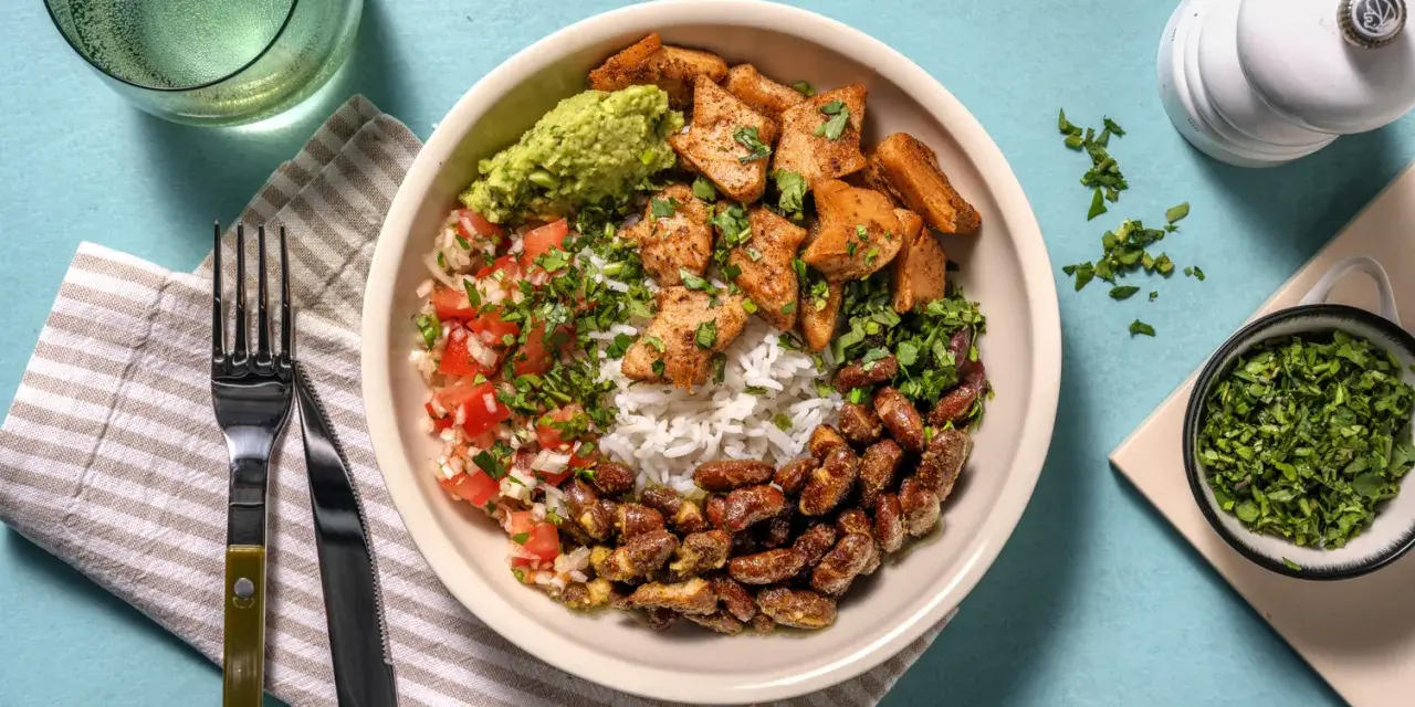 Bowl con arroz, frijoles, guacamole, pico de gallo y trozos de boniato y tofu, un festín de comidas vegetarianas ricas en proteínas.