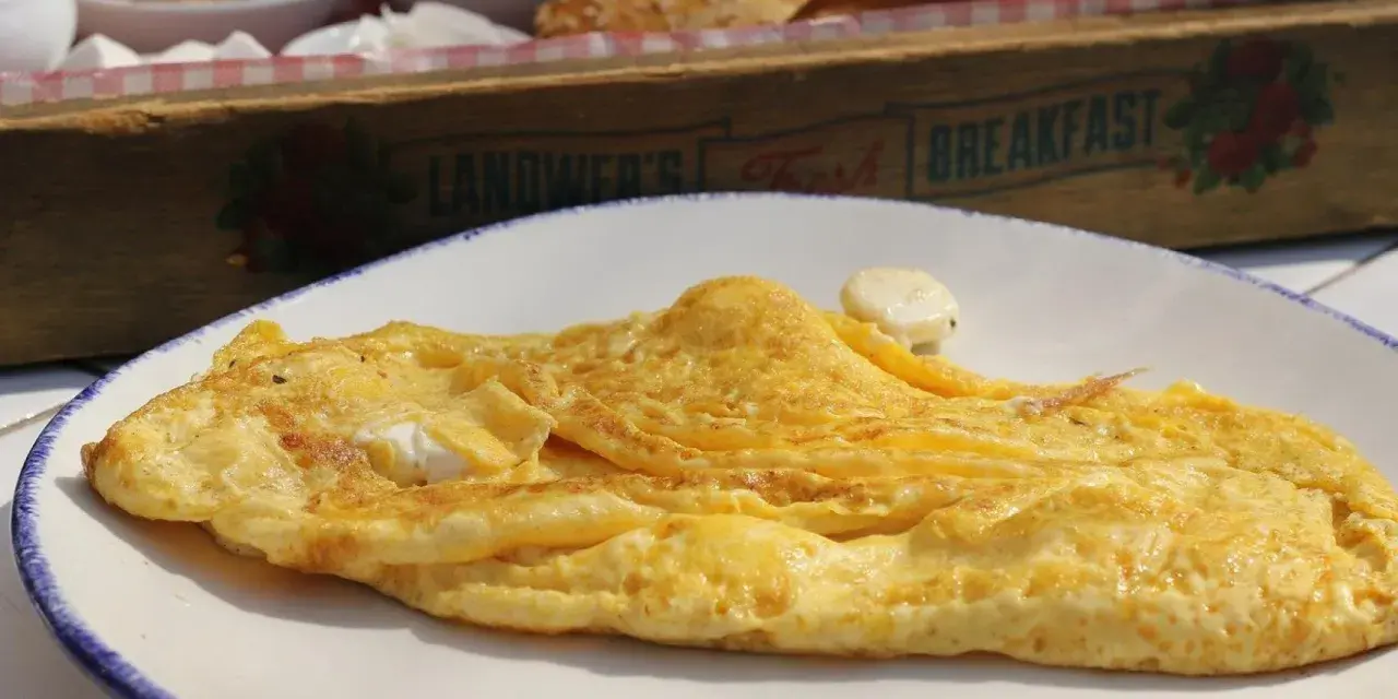 Tortilla francesa dorada en plato blanco, con un toque de queso. ¡Cuidado, la tortilla francesa engorda si no la acompañas con ensalada!