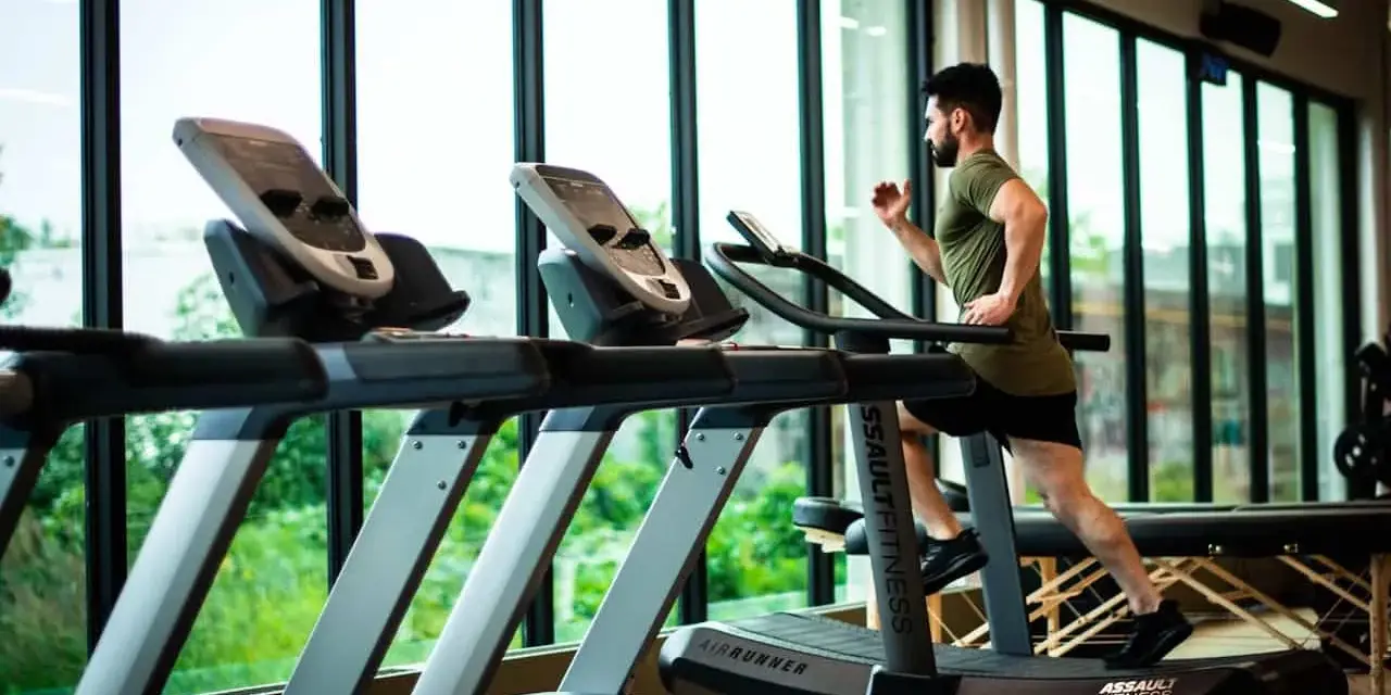 Hombre corriendo en cinta. ¿Qué es mejor bici estática o cinta de correr? La cinta ofrece un entrenamiento más completo.