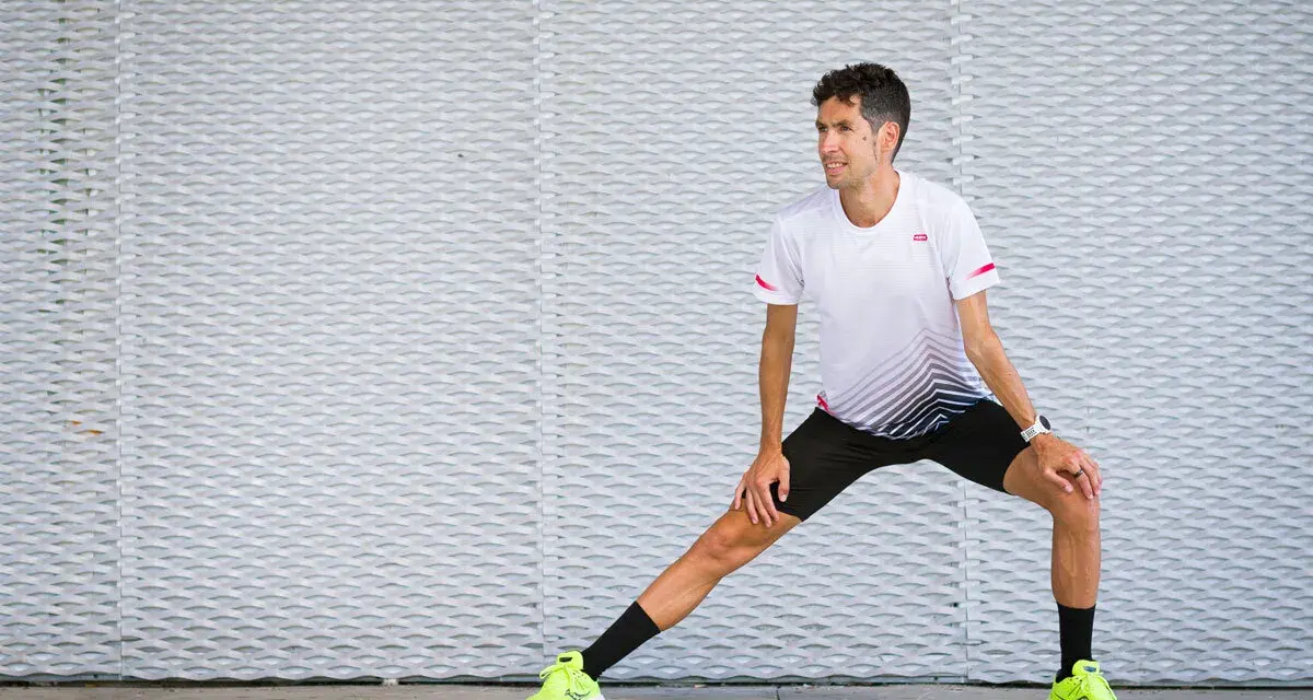 Corredor realiza estiramientos antes de correr, preparándose para su entrenamiento.
