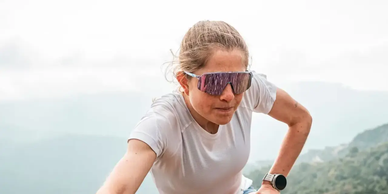 Mujer con gafas de correr, concentrada en su ascenso por la montaña.