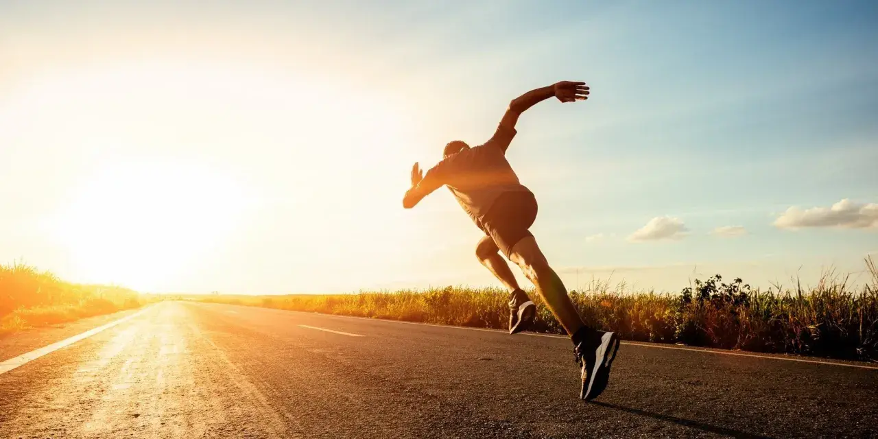 Corredor en una carretera al atardecer, experimentando lo que es un tempo run: un esfuerzo sostenido y desafiante.