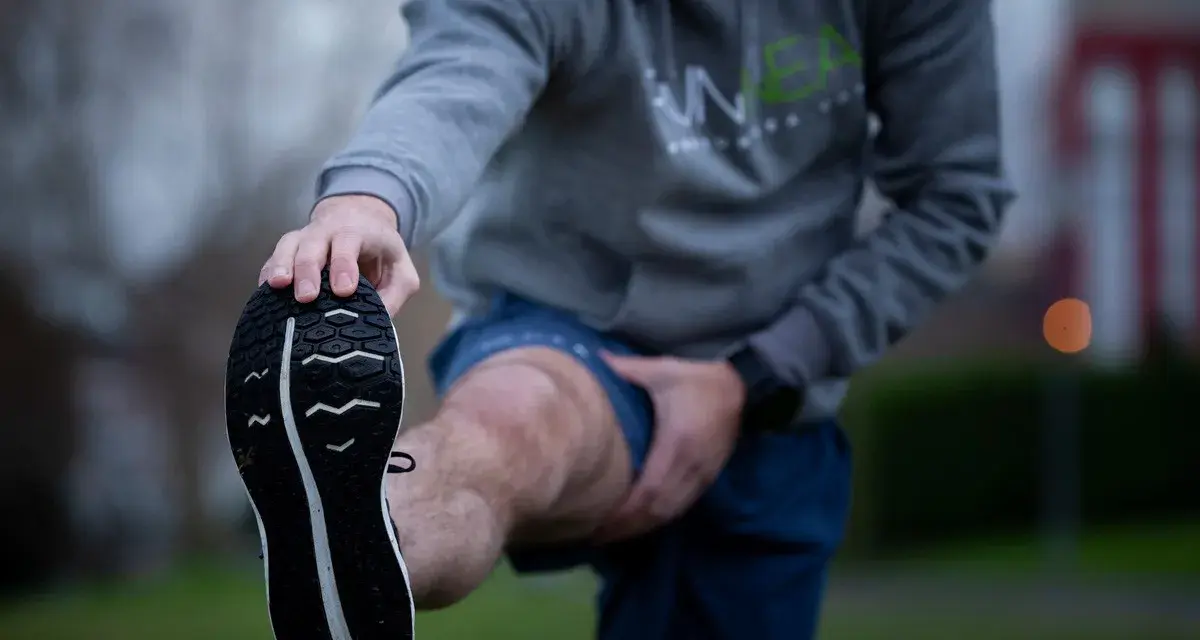Hombre estirando la pierna antes de correr con agujetas.
