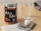 Un bote de creatina monohidrato, un vaso de agua y una báscula digital con una cucharada de polvo. Descubre los beneficios de la creatina monohidrato para tu entrenamiento.