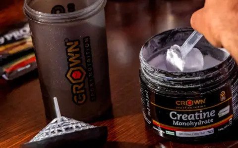 Un corredor prepara su batido con creatina monohidratada Crown Sport Nutrition para potenciar su rendimiento.