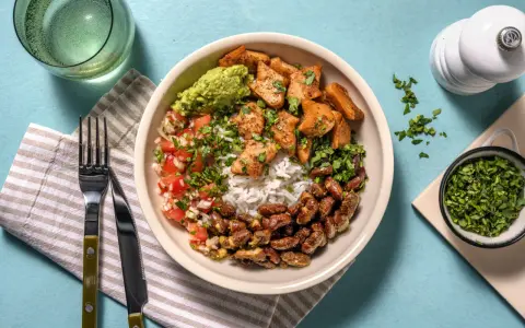 Bowl con arroz, frijoles, guacamole, pico de gallo y trozos de boniato y tofu, un festín de comidas vegetarianas ricas en proteínas.