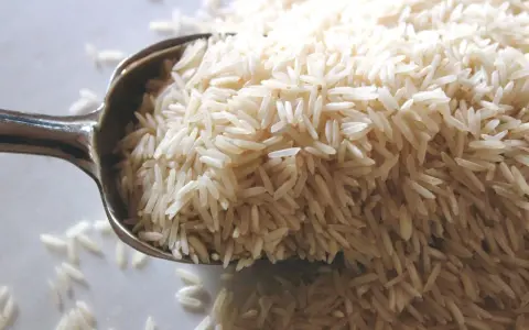 Cuchara llena de arroz basmati. Aunque la crema de arroz engorda, este grano es un carbohidrato básico.