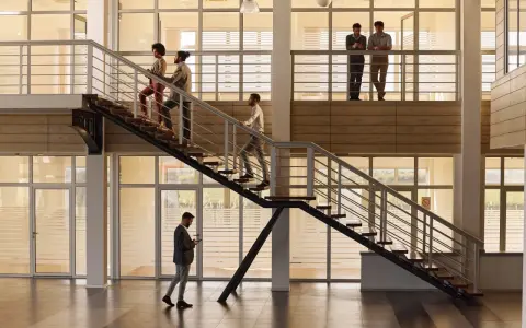 Personas subiendo escaleras, disfrutando de los beneficios de la actividad física en un moderno edificio de oficinas.
