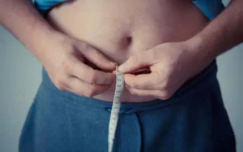 Man measuring waist with tape. A step towards understanding como activar la autofagia for better health.
