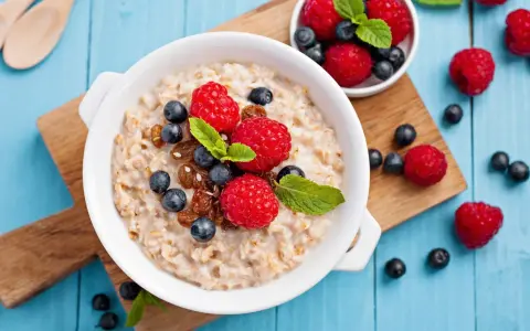 Un tazón de avena con frambuesas, arándanos y pasas. ¡Cuidado! La avena engorda si no se consume con moderación.