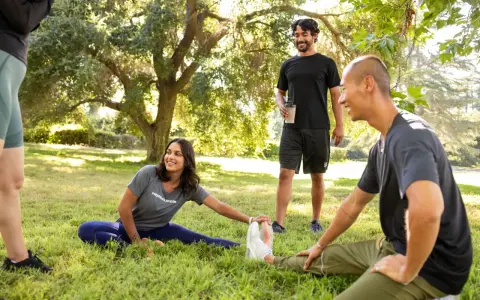 Un grupo de amigos hace estiramientos en un parque. Uno de ellos, que bebe un batido, bromea diciendo que "la creatina engorda", pero todos se ríen y siguen entrenando.