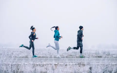 Tres personas corren en un paisaje nevado con ropa para correr en invierno.