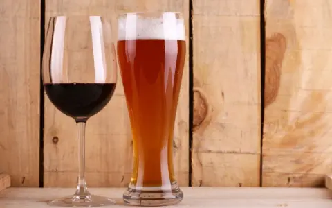 Copa de vino tinto y vaso de cerveza dorada con espuma. ¿Qué engorda más la cerveza o el vino? La respuesta está en las calorías.