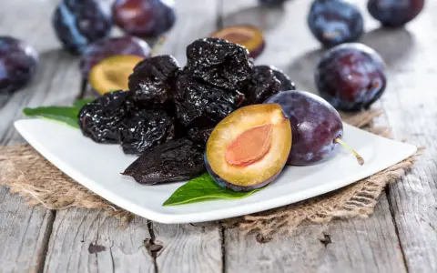 Ciruelas pasas y ciruelas frescas en un plato blanco, perfectas para comer ciruelas pasas por la noche.