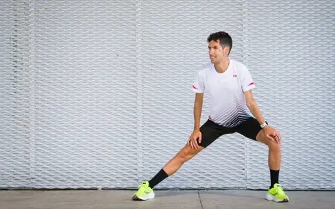 Corredor realiza estiramientos antes de correr, preparándose para su entrenamiento.
