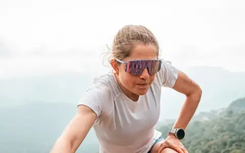 Mujer con gafas de correr, concentrada en su ascenso por la montaña.