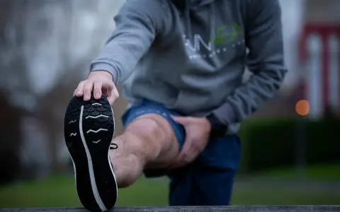 Hombre estirando la pierna antes de correr con agujetas.