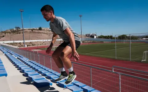 Corredor realiza ejercicios pliométricos subiendo escaleras en un estadio.