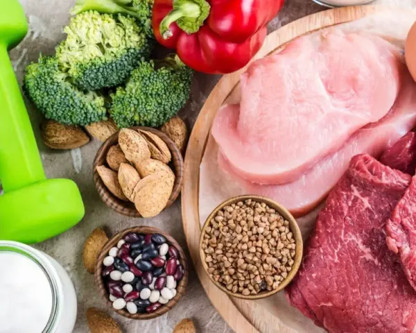 Alimentos para una dieta para ganar masa muscular y definir: pesas, brócoli, pimientos, carnes, huevos, yogur, almendras y legumbres.