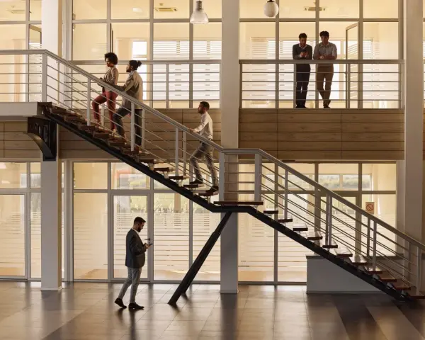 Personas subiendo escaleras, disfrutando de los beneficios de la actividad física en un moderno edificio de oficinas.