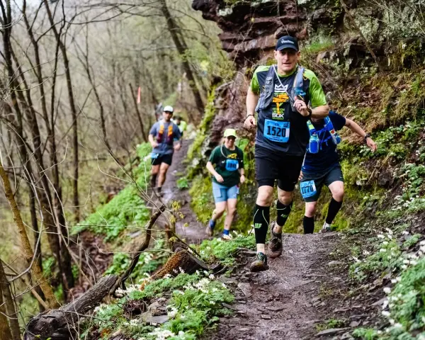 Corredores en un sendero boscoso, demostrando la resistencia necesaria para los ejercicios de fuerza para trail running.